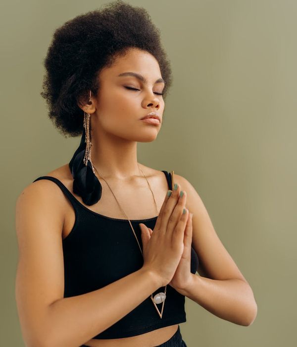 Woman in a peaceful yoga pose against a jade green background.
